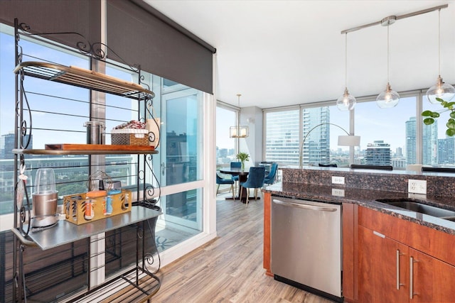 kitchen featuring brown cabinets, dishwasher, light wood-style flooring, dark stone countertops, and pendant lighting