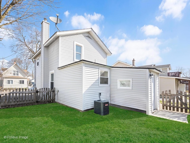 back of house with fence, a chimney, a yard, and cooling unit