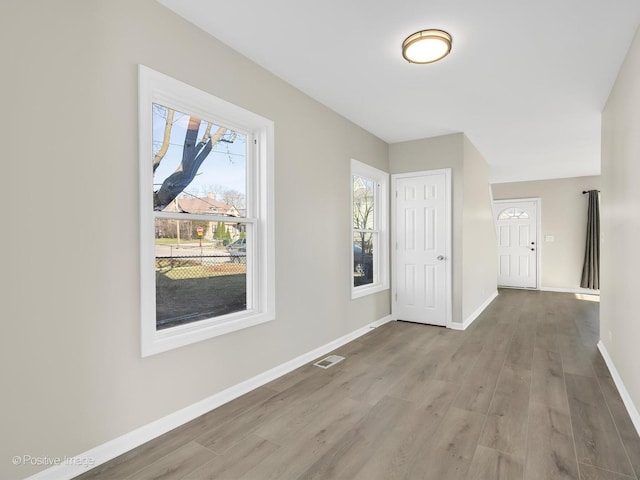 foyer featuring wood finished floors, visible vents, and baseboards