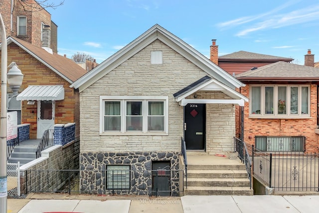 view of front of house featuring stone siding and fence