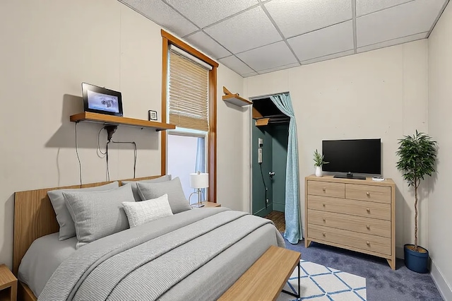 carpeted bedroom featuring a drop ceiling
