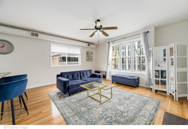 living area with baseboards, visible vents, ceiling fan, and wood finished floors