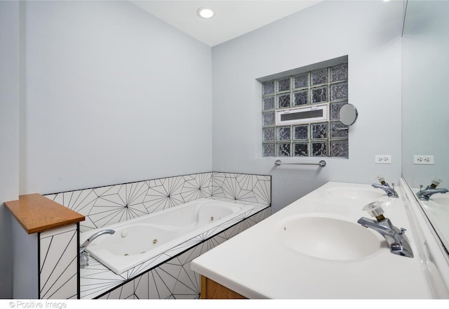 bathroom with double vanity, a jetted tub, and a sink