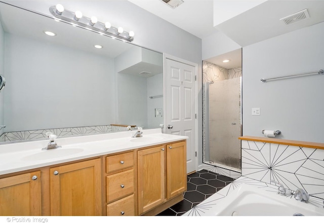 full bath with a sink, double vanity, a stall shower, and visible vents