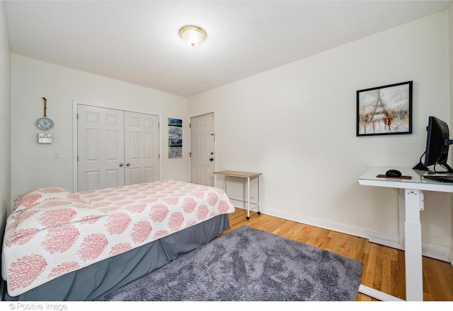 bedroom with a closet, wood finished floors, and baseboards