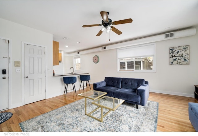 living area featuring visible vents, wood finished floors, baseboards, and ceiling fan
