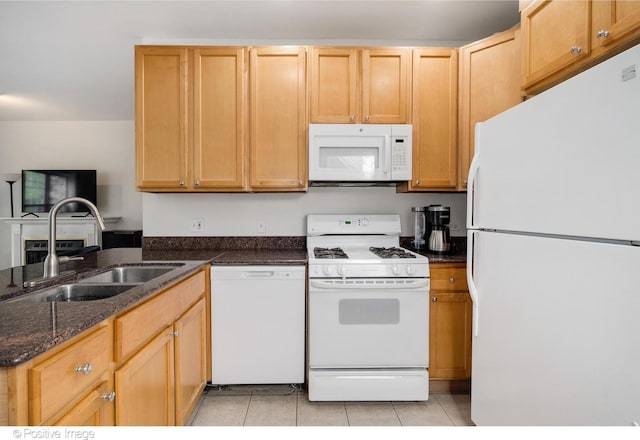 kitchen with light tile patterned floors, white appliances, a sink, a peninsula, and dark stone countertops