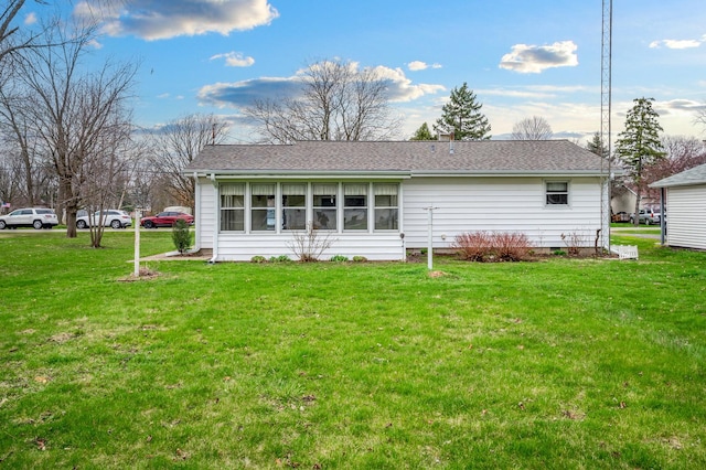 rear view of property with a yard and a shingled roof