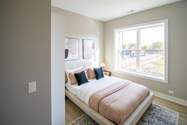 bedroom featuring light wood finished floors, baseboards, and visible vents