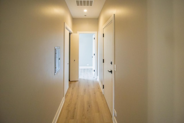 hallway featuring light wood-style floors, visible vents, and baseboards