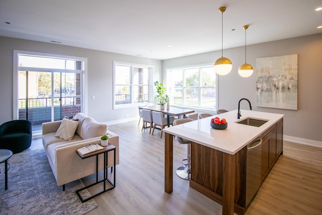 kitchen with a sink, baseboards, and light wood-style floors