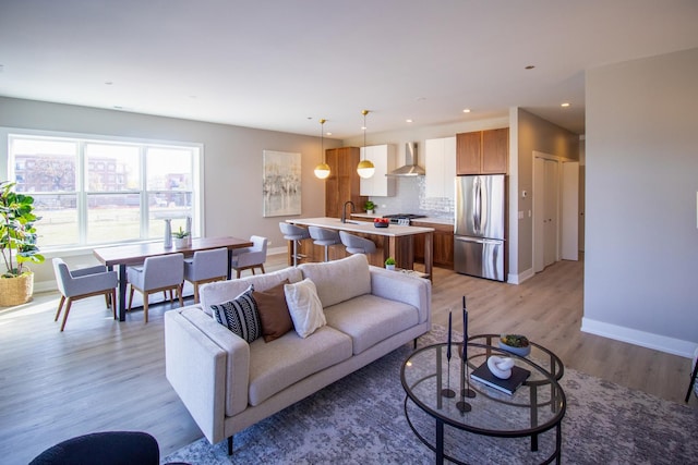 living area featuring light wood-style floors, baseboards, and recessed lighting