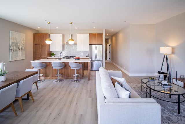 living area featuring light wood-style flooring, baseboards, and recessed lighting