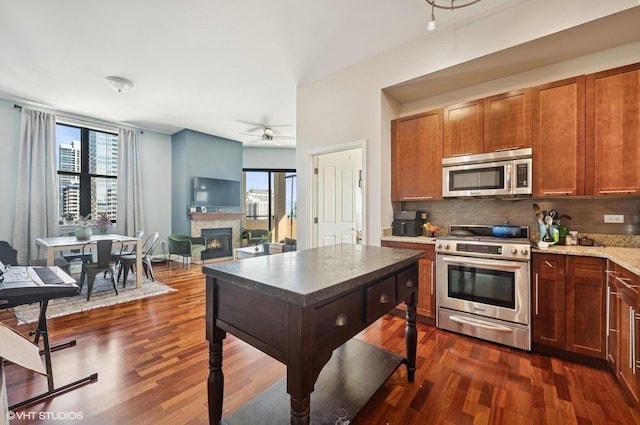 1464 S Michigan Ave Unit 1401, Chicago, IL 60605 - kitchen featuring appliances with stainless steel finishes, decorative backsplash, a warm lit fireplace, and dark wood-type flooring