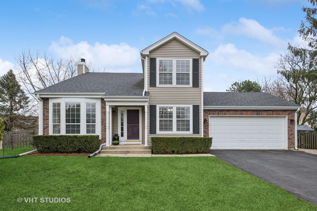 3 Waterbury Ct, Lake Zurich, IL 60047 - traditional-style home with aphalt driveway, brick siding, fence, and a front yard