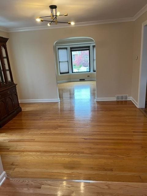 1911 N 73rd Ave N, Elmwood Park, IL 60707 - unfurnished room featuring ornamental molding, light wood finished floors, arched walkways, and a chandelier