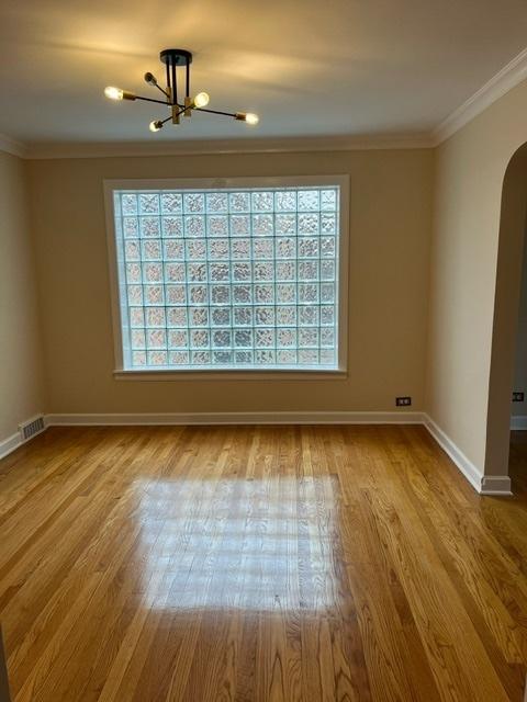 1911 N 73rd Ave N, Elmwood Park, IL 60707 - empty room with arched walkways, a chandelier, plenty of natural light, wood finished floors, and crown molding