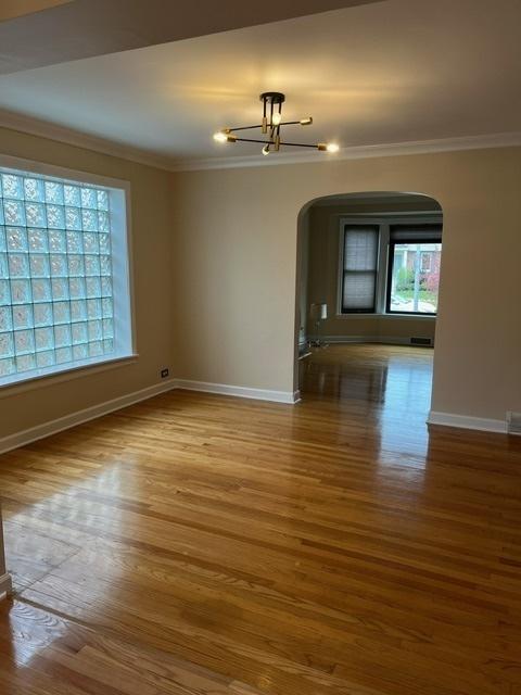 1911 N 73rd Ave N, Elmwood Park, IL 60707 - spare room with arched walkways, crown molding, wood finished floors, and a chandelier