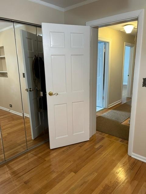 1911 N 73rd Ave N, Elmwood Park, IL 60707 - unfurnished bedroom featuring ornamental molding, a closet, and light wood-style flooring