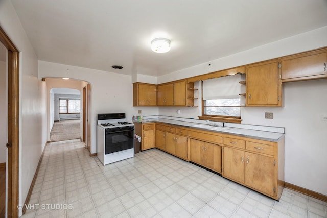 3101 S 53rd Ct, Cicero, IL 60804 - kitchen featuring open shelves, a sink, arched walkways, gas range gas stove, and baseboards