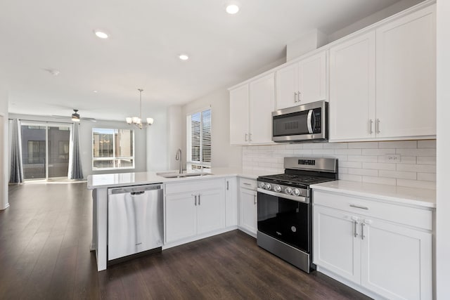 kitchen featuring a peninsula, light countertops, a sink, stainless steel appliances, and decorative backsplash