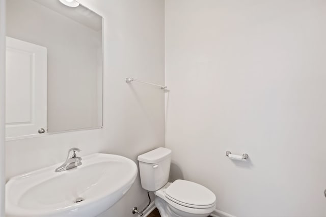 bathroom with baseboards, a sink, and toilet