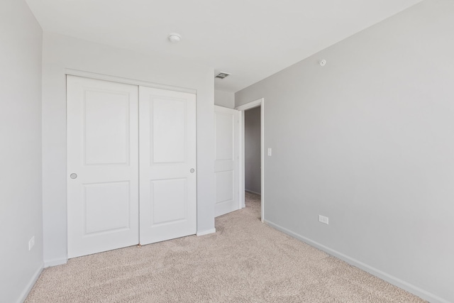 unfurnished bedroom with carpet flooring, visible vents, a closet, and baseboards