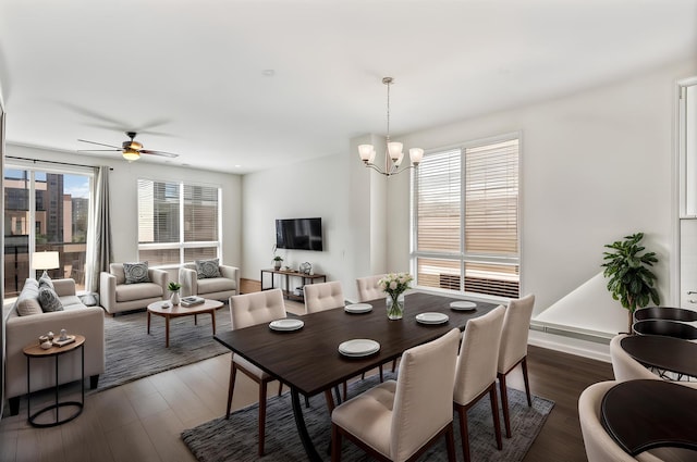 dining area featuring dark wood-style floors and ceiling fan with notable chandelier