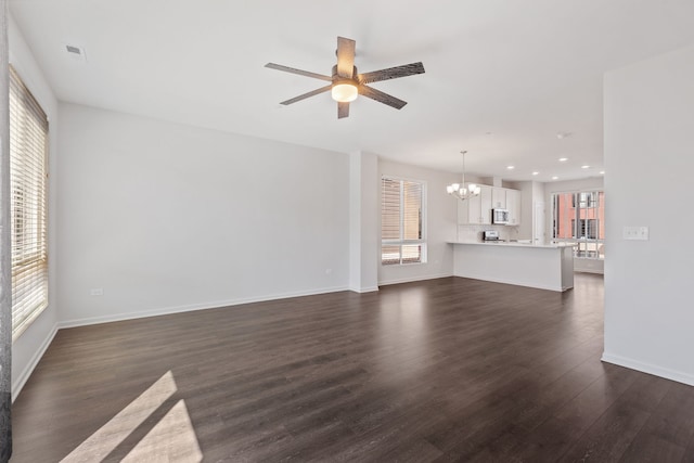 unfurnished living room with dark wood-style flooring, baseboards, recessed lighting, visible vents, and ceiling fan with notable chandelier