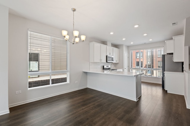 kitchen with stainless steel microwave, a sink, dark wood-style floors, and white cabinets