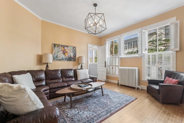 living room with radiator heating unit, wood finished floors, a notable chandelier, and crown molding