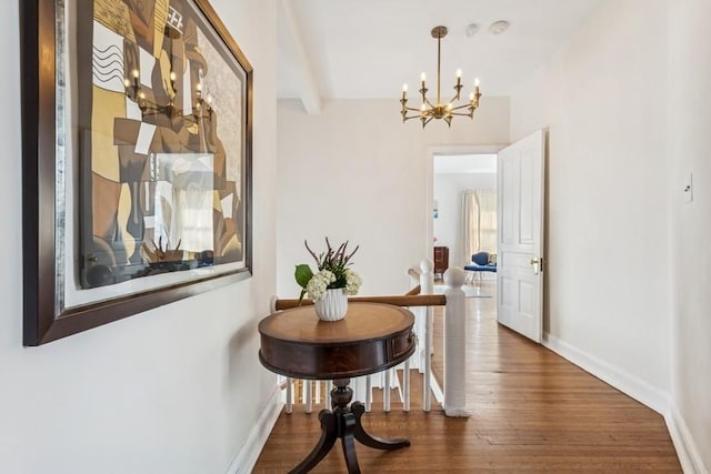 hallway with an inviting chandelier, wood finished floors, and baseboards