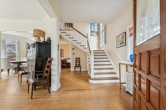 entryway with light wood-type flooring, baseboards, and stairs