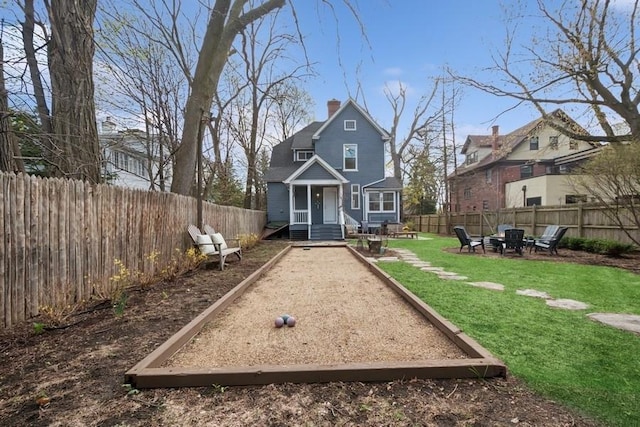 rear view of house with a chimney, fence private yard, and a yard