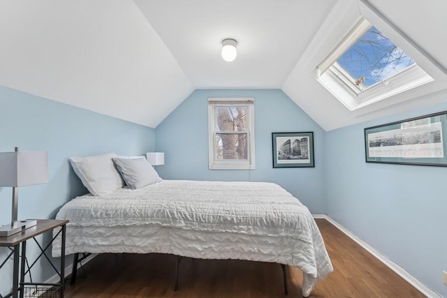 bedroom with baseboards, wood finished floors, and vaulted ceiling with skylight