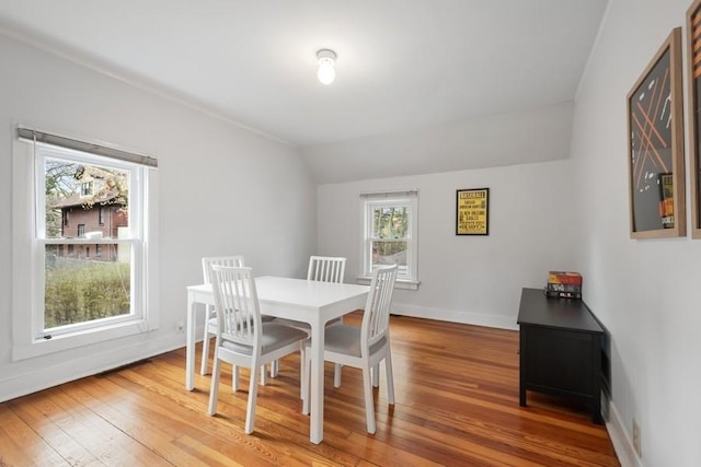 dining space with lofted ceiling, light wood-style flooring, and baseboards