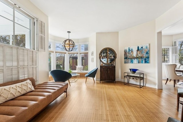 living area featuring baseboards, a healthy amount of sunlight, a chandelier, and light wood finished floors