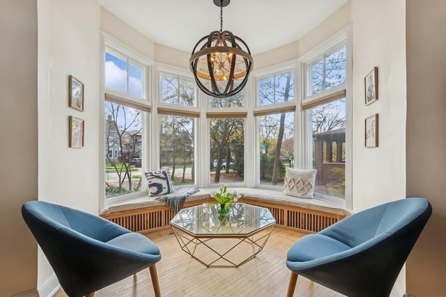 sunroom featuring an inviting chandelier, wood finished floors, and a high ceiling