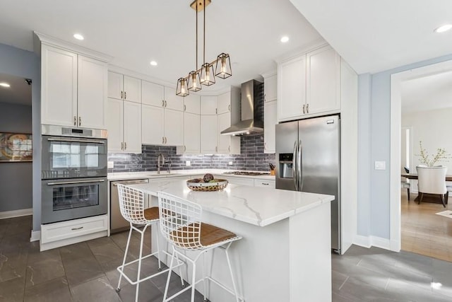 kitchen featuring tasteful backsplash, a sink, white cabinetry, wall chimney exhaust hood, and appliances with stainless steel finishes