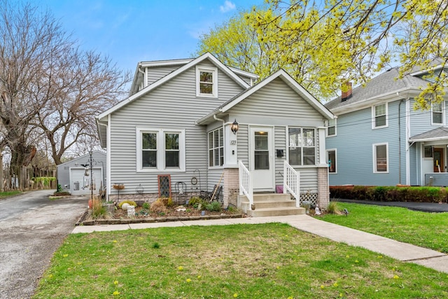 123 W York Ave, West Chicago, IL 60185 - bungalow-style house featuring a front lawn, a garage, entry steps, an outbuilding, and cooling unit