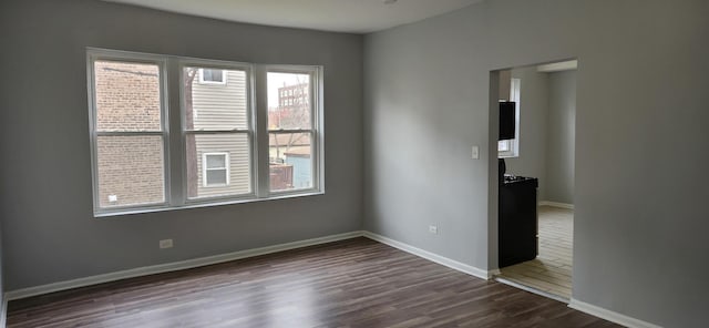 spare room featuring dark wood-type flooring and baseboards