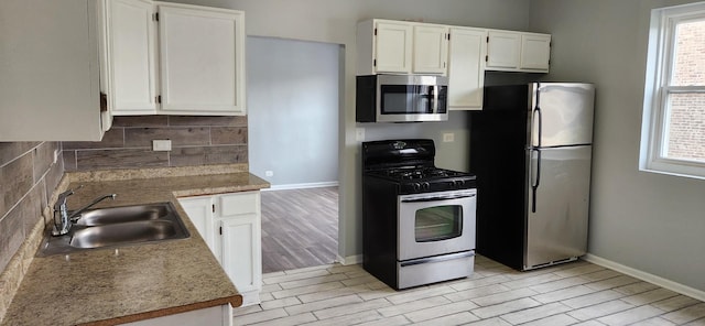kitchen with backsplash, a sink, stainless steel appliances, and plenty of natural light