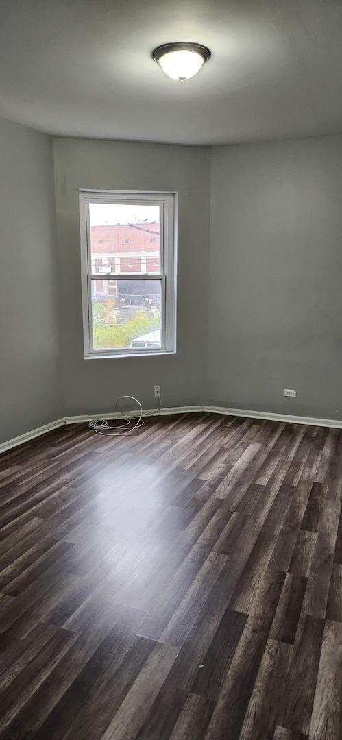 empty room featuring baseboards and dark wood-style floors