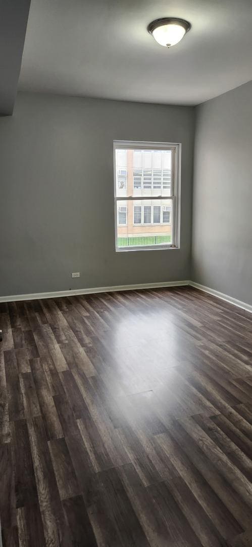 empty room with baseboards and dark wood-type flooring