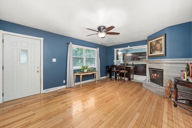910 Sarah Ln, Aurora, IL 60502 - living room featuring ceiling fan, light wood-style flooring, a fireplace, and baseboards
