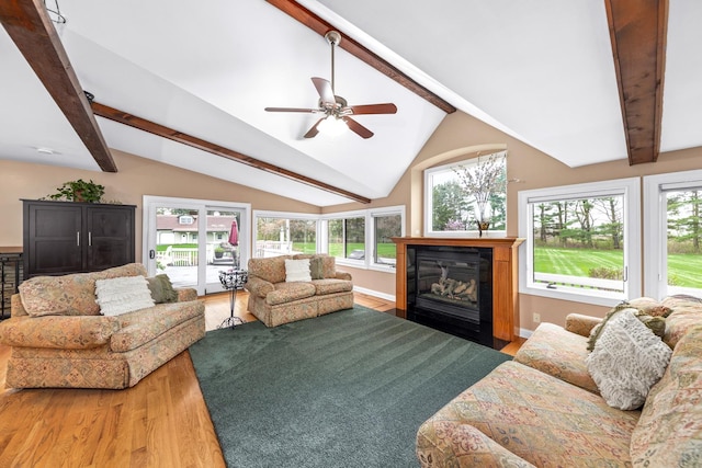 living room with a ceiling fan, lofted ceiling with beams, a fireplace with flush hearth, and wood finished floors