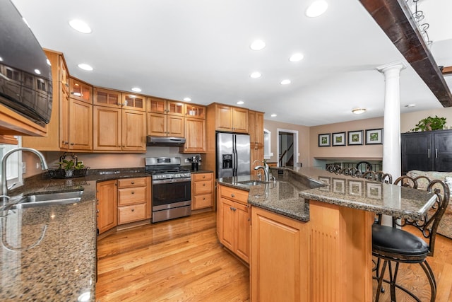 kitchen with stainless steel appliances, a kitchen breakfast bar, a sink, and light wood finished floors