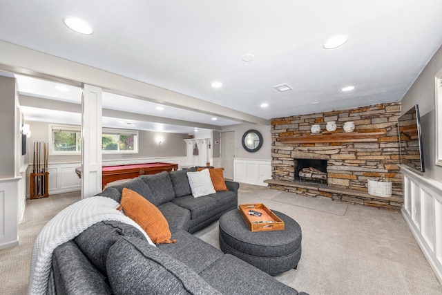 living area with light colored carpet, a fireplace, wainscoting, a decorative wall, and recessed lighting