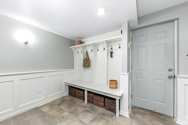 mudroom with wainscoting, a decorative wall, and stone finish floor