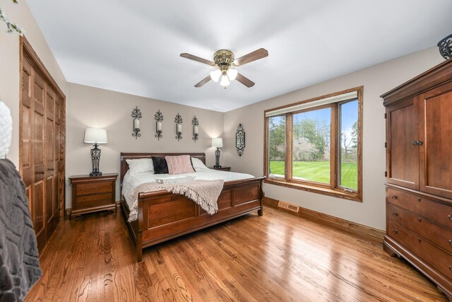 bedroom featuring baseboards, ceiling fan, light wood-type flooring, and visible vents